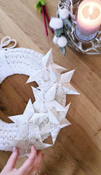 Dieser handgefertigte Wandkranz kombiniert zarte Häkelkunst mit Sternen aus Buchseiten – für alle, die Recycling Kunst lieben und auf Wanddeko Ideen stehen.