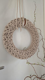 Dieser handgefertigte Wandkranz besticht durch sein elegantes Jasmin-Häkelmuster, das ihm eine besonders feine Struktur verleiht. Seine Naturfarben und sein minimalistisches Design machen ihn zu einem perfekten skandinavischen Wohnaccessoire für dein Zuhause.
