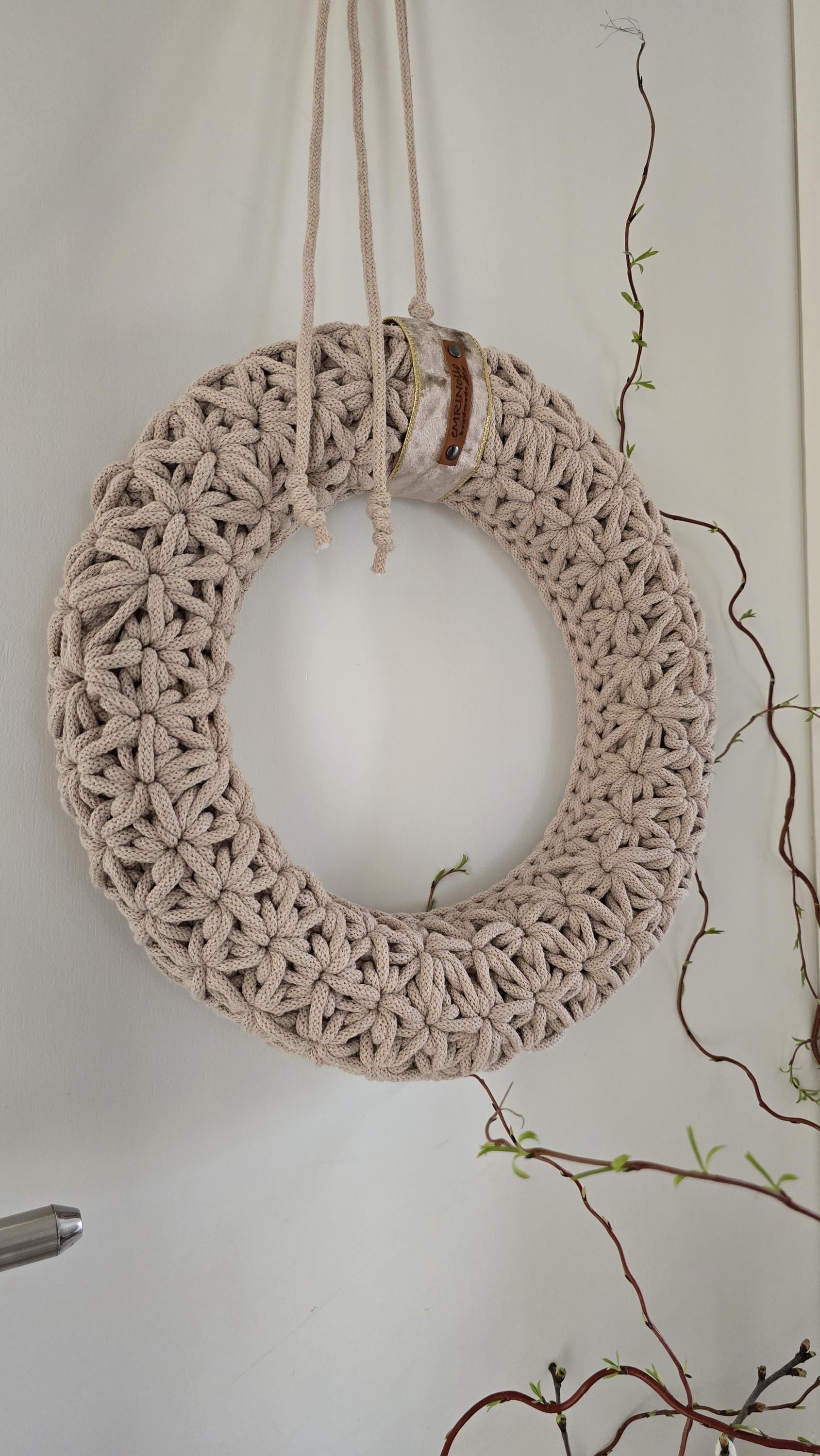 Dieser handgefertigte Wandkranz besticht durch sein elegantes Jasmin-Häkelmuster, das ihm eine besonders feine Struktur verleiht. Seine Naturfarben und sein minimalistisches Design machen ihn zu einem perfekten skandinavischen Wohnaccessoire für dein Zuhause.