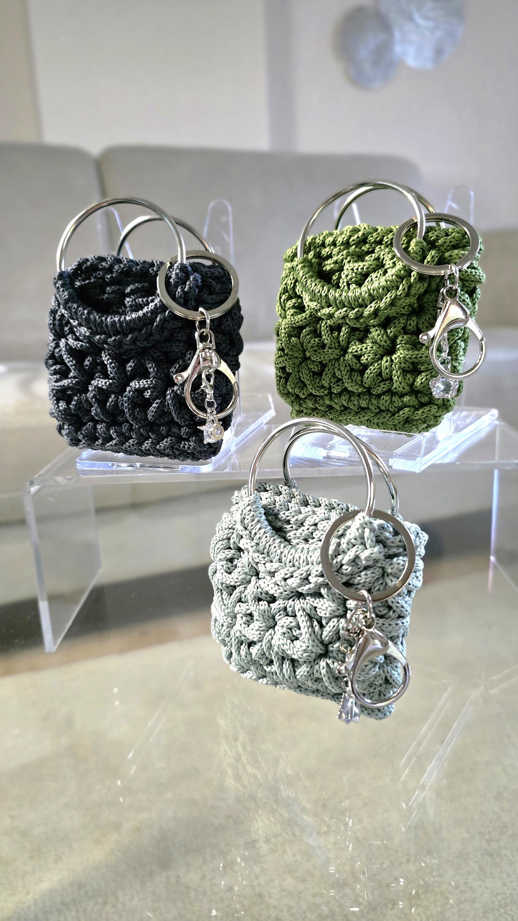 Eckiger Taschenanhänger im Jasminmuster mit großen Ringgriffen in Avocado als modernes Bag Charm Accessoire.