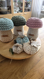 Zwei handgefertigte Pilz-Aufbewahrungskörbe aus Baumwollkordel im 2er-Set. Links Größe S mit 15 cm Durchmesser, rechts Größe M mit 18 cm Durchmesser, platziert auf einem hellen Kinderschreibtisch.