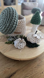 Handgearbeiteter Aufbewahrungskorb in Pilzform aus beiger Baumwollschnur und dunkelroter Kappe, herbstlich dekoriert mit ein paar Tannenzapfen auf einem hellen Holzregal.