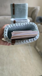 Vier kleine Baumwollkörbe mit rechteckiger Form und braunen Labels auf einer weißen Ablage unter einem Bilderregal.